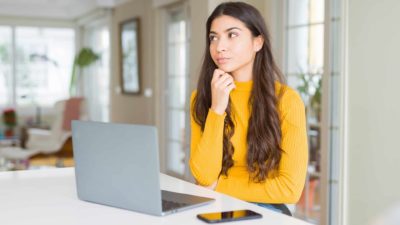 Young woman thinking with laptop open.
